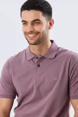 Remera polo de piqué color lila, con cuello camisero, cierre frontal de dos botones y mangas cortas. Presenta un pequeño bordado sutil en el pecho.
