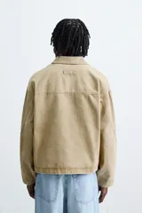 Cazadora de corte relajado confeccionada en tejido de algodón con efecto lavado. Presenta cuello solapa, cierre frontal con cremallera, bolsillos laterales en la cadera y mangas terminadas en puños con botón.