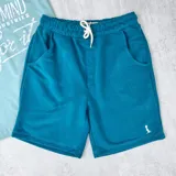 Short deportivo azul petróleo con cintura elástica ajustable con cordón y bolsillos laterales.