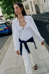 Camisa blanca de algodón con cuello solapa, manga larga y cierre frontal de botones.