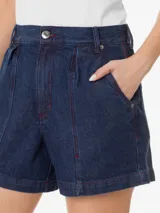 Short de jean azul oscuro con costuras burdeos, de tiro alto y corte holgado. Presenta trabillas en la cintura, dos bolsillos delanteros tipo navaja, pliegues delanteros y cierre frontal con cremallera y botón.