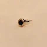 Anillo tipo sello fabricado en plata 925 con detalles en oro 9k, presenta una piedra central de onix negro de forma circular con un borde texturizado.