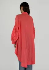 Blusa color coral con cuello camisero, mangas largas con detalles de calado y bajo irregular.