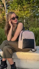 Mochila urbana de diseño combinado, confeccionada en tela resistente con bolsillo frontal y detalles en cuero sintético. Cuenta con compartimento principal con cierre y correas ajustables.