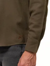 Camisa de franela color azul marino, de manga larga, con cuello abotonado, un bolsillo frontal y cierre de botones.