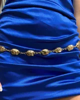 Cinturón de cadena compuesto por eslabones metálicos dorados con piezas irregulares de acabado brillante.