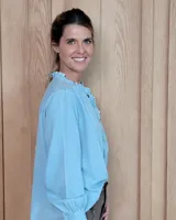 Blusa de manga larga con estampado de rayas verticales finas en tono beige. Presenta cuello redondo con volados, cierre frontal parcial con botones y puños con volados.