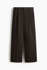 Pantalón sastrero de corte holgado y piernas amplias, color marrón oscuro, con pinzas delanteras, pliegues planchados, pretina con trabillas y bolsillos laterales al bies.