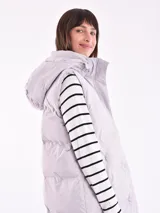 Chaleco largo acolchado color lila con capucha y bolsillos laterales.