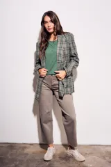 Blazer de corte recto con estampado de cuadros en tonos verdes y grises. Presenta solapas clásicas, cierre frontal y bolsillos laterales.