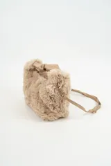Cartera de mano confeccionada en piel sintética de textura suave y peluda, color beige. Presenta un asa superior fruncida de material liso y una correa larga ajustable y extraíble con herrajes metálicos dorados.