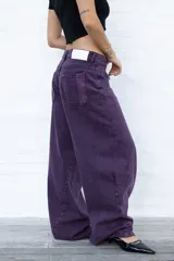Jean de mujer color violeta oscuro, de corte holgado y tiro bajo. Presenta un efecto lavado y bolsillos traseros con costuras decorativas.