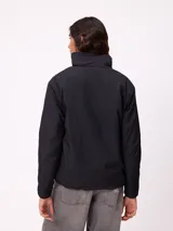Campera reversible de diseño holgado, con un lado en tejido sherpa estampado con motivos florales en tonos negro y beige, y el otro lado en nylon negro. Cuenta con cierre frontal y cordones ajustables en el ruedo.