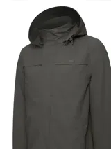 Campera impermeable de color verde oscuro, con capucha ajustable y desmontable, cierre frontal oculto y ventilación bajo las axilas. Fabricada con poliéster reciclado, cuenta con costuras selladas y membrana de alta impermeabilidad.