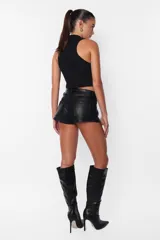 Short negro de cuerina, tiro medio, con bolsillos delanteros y traseros, presillas en la cintura y cierre con botón metálico y cremallera.