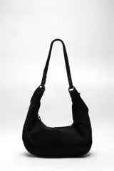Bolso tote hobo de ante negro suave, con dos asas largas para el hombro unidas mediante argollas metálicas, cierre superior con cremallera y cuerpo blando de gran capacidad.