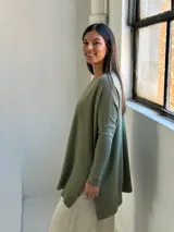 Sweater de tejido de punto color verde oliva, con cuello redondo, mangas largas y corte holgado con costura central vertical.