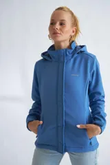 Campera de neopreno color rojo con capucha ajustable, cierre frontal completo y bolsillos laterales. Presenta puños ajustables con velcro y un parche circular decorativo en la manga izquierda.