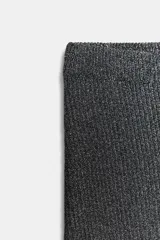 Falda midi de tiro alto, corte recto y cintura elástica, confeccionada en tejido de punto gris oscuro con hilo metalizado que le da un aspecto brillante.