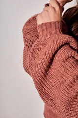 Sweater de tejido bouclé texturado color beige, con cuello redondo y mangas largas holgadas de corte amplio.
