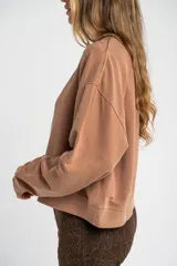 Buzo lila oversize confeccionado en 100% algodón, con cuello redondo, mangas largas y puños y dobladillo acanalados. Presenta un pequeño detalle bordado en el bajo.