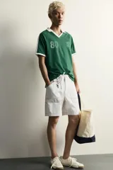 Polo de fútbol retro color verde oscuro, de corte regular fit, con cuello solapa blanco, mangas cortas con ribetes blancos y bandas en los hombros. Cuenta con estampado frontal del número 80 y un gráfico con efecto lavado.