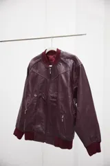 Campera tipo bomber confeccionada en cuero ovino color bordó, con cierre frontal, bolsillos laterales con cierre y puños y cintura de tejido elástico acanalado.