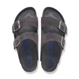 Sandalias Birkenstock modelo Arizona de dos tiras ajustables con hebillas metálicas. Confeccionadas en gamuza color gris carbón, cuentan con la clásica plantilla de corcho anatómica y suela de goma negra.