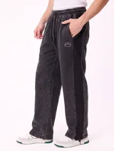 Pantalón jogger holgado de color gris con efecto acid wash y franjas laterales negras. Cuenta con cintura elástica con cordón ajustable y bolsillos laterales.