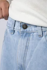 Jean de corte mom oversize, color negro lavado, con diseño de cinco bolsillos y cierre frontal con botón y cremallera.