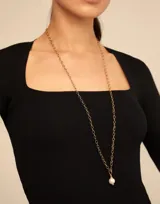 Dije colgante dorado con una perla blanca.