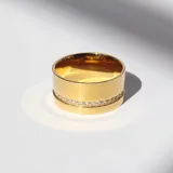 Anillo dorado ancho con una línea de cristales incrustados en uno de sus laterales.