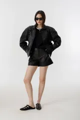 Chaqueta negra de cuero de oveja con apliques tribales en gamuza de cabra al tono, forro capitoneado de poliéster, cuello camisero redondeado, bolsillos frontales, bolsillo interno y botones metálicos a presión forrados.