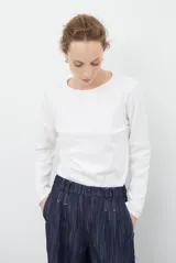 Remera de manga larga con cuello redondo, confeccionada en tejido de punto gris melange con costuras visibles en contraste.
