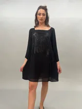 Vestido corto de gasa con estampado abstracto en tonos grises y negros. Tiene escote cuadrado, mangas 3/4 plisadas, bolsillos laterales ocultos y espalda levemente escotada con elástico a la altura de la cintura.