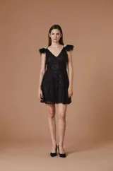 Vestido corto de encaje blanco con silueta evasé, escote en V y detalle de plumas desmontables en los hombros. Presenta una textura con destellos sutiles y cintura definida.