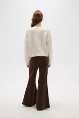 Sweater negro de punto con escote en V profundo y detalle de encaje en el borde del cuello. Presenta mangas largas con puños acanalados y un corte holgado.