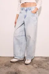 Jean de corte baggy con silueta barrel, tiro medio y lavado claro. Presenta costuras reforzadas en las rodillas y ruedo con doblez.