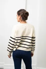 Saco de punto con cierre frontal, diseño a rayas horizontales negras sobre base color crudo, de manga larga y corte recto.