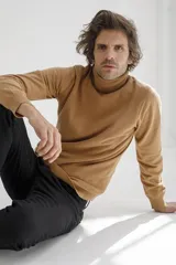 Sweater de cuello alto en color tostado, confeccionado en tejido de punto con textura en el panel frontal y mangas lisas. Presenta puños y ruedo acanalados.