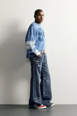 Camiseta boxy fit de color azul con efecto lavado vintage, cuello redondo y mangas por debajo del codo. Presenta un gran número '94' estampado en el frente y franjas horizontales en las mangas.