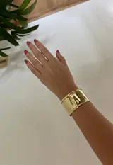 Pulsera rígida dorada, tipo brazalete, hecha en bronce.