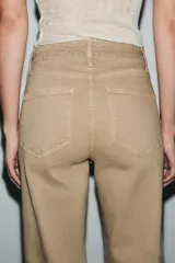 Jeans de tiro alto con corte wide leg y largo completo. Presenta diseño de cinco bolsillos, trabillas en la cintura y cierre frontal con cremallera y botón, con un acabado de efecto lavado.