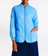 Campera bomber celeste con diseño acolchado de rombos, cuello redondo de punto, cierre frontal con cremallera y mangas largas con puños elásticos.