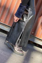 Pantalón Oxford de cuero negro con cierre frontal y pasamanería plateada en los tajos laterales.