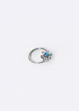 Piercing de titanio plateado con forma de aro y dije de flor con ópalo celeste en el centro y pétalos de zirconia. Se desarma en dos piezas.