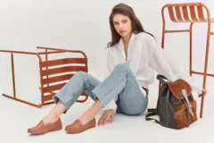 Mocasines de cuero color dorado con acabado texturizado, diseño clásico de punta redondeada y costuras visibles en el empeine. Cuentan con suela plana y flexible.