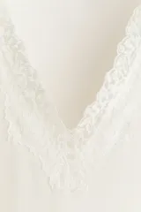 Remera de manga larga de punto acanalado color blanco, con ajuste entallado y escote en V ribeteado con encaje.