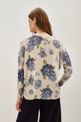 Sweater de punto con diseño estampado de flores en tonos azules y verdes sobre base color crema. Presenta cuello redondo y mangas largas con corte holgado.