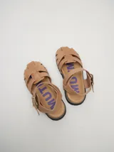 Sandalias de cuero marrón con tiras entrecruzadas, suela de goma negra con pespuntes blancos y hebilla lateral.